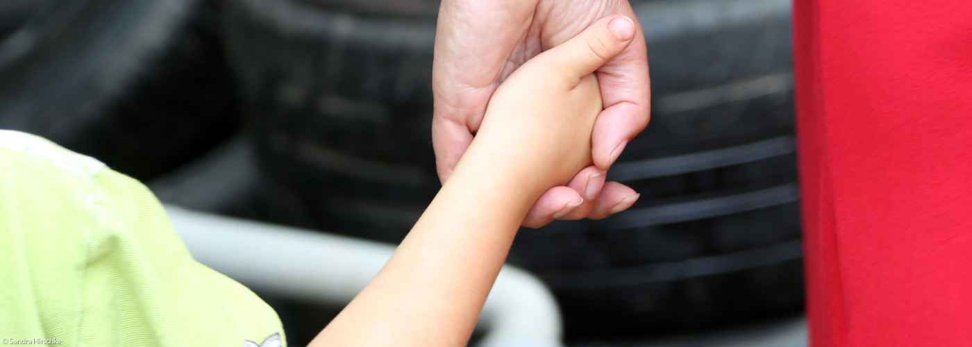 Kind an der Hand einer Erzieherin