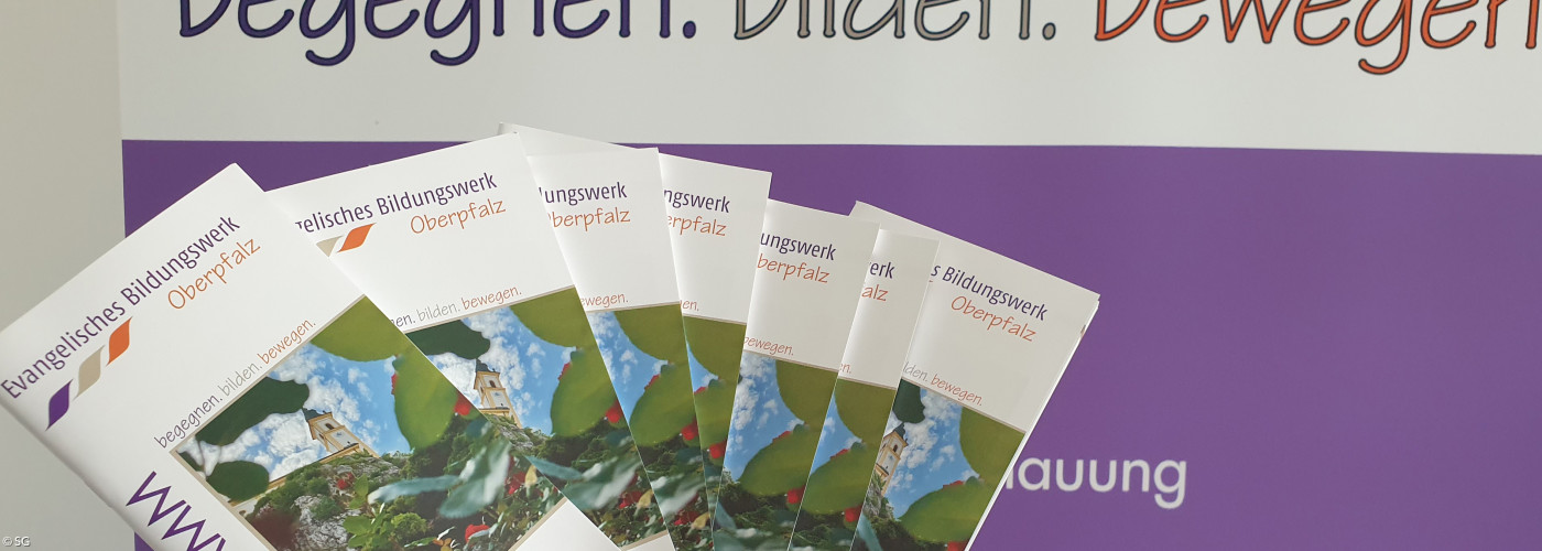 Eine Hand hält mehrere EBW-Programmhefte