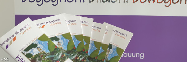 Eine Hand hält mehrere EBW-Programmhefte