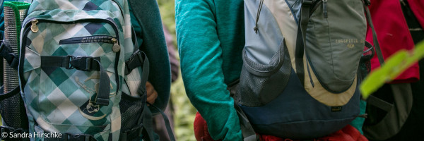 Drei Personen mit Wanderrucksäcken auf dem Rücken