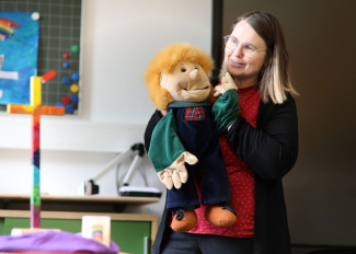 Eine Religionslehrerin erzählt mit einer Handpuppe eine Geschichte
